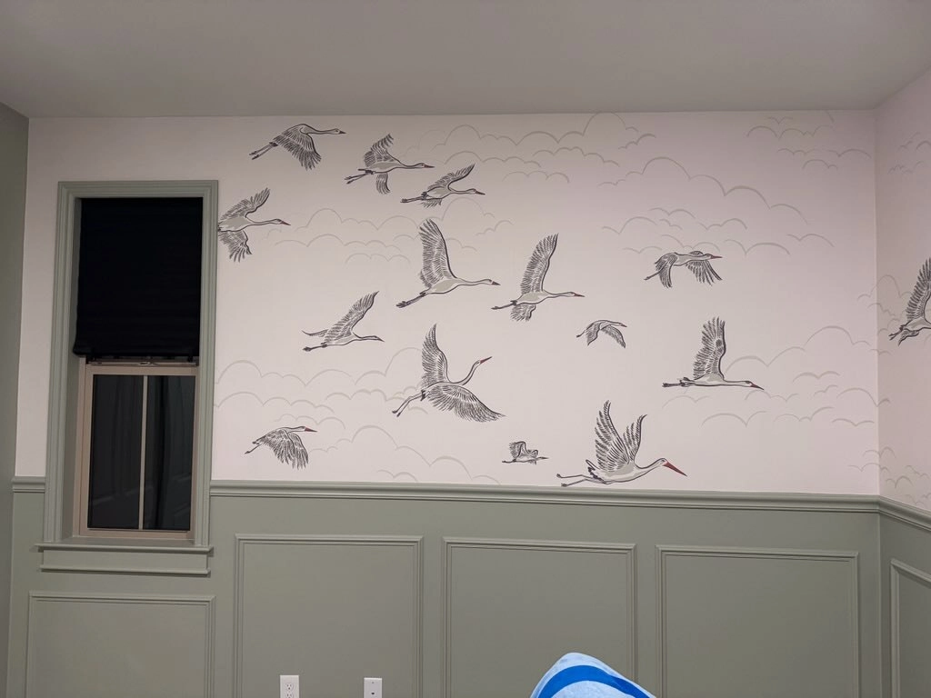 Light wallpaper patterned with birds above painted wall trim.
